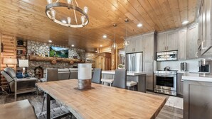 Une cuisine moderne avec des meubles en bois, des appareils électroménagers en acier inoxydable et une grande table à manger.