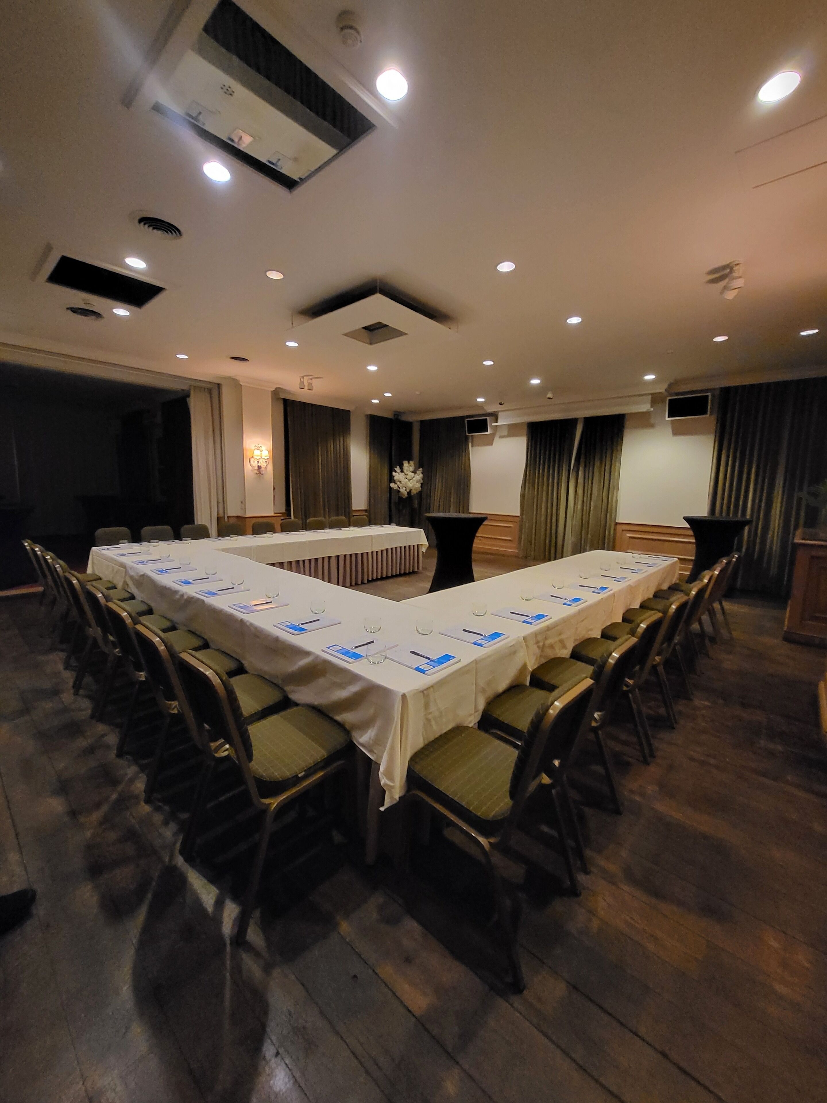 Una sala conferenze con un lungo tavolo, sedie e un podio.