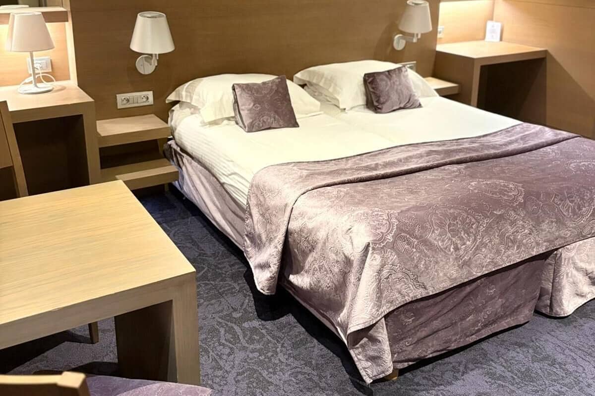 A hotel room with a bed, bedside tables, a desk, and a chair.