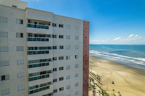 A high-rise hotel with multiple balconies overlooking a beach. - CANTINHO DA FAMÍLIA  (Praia Grande)