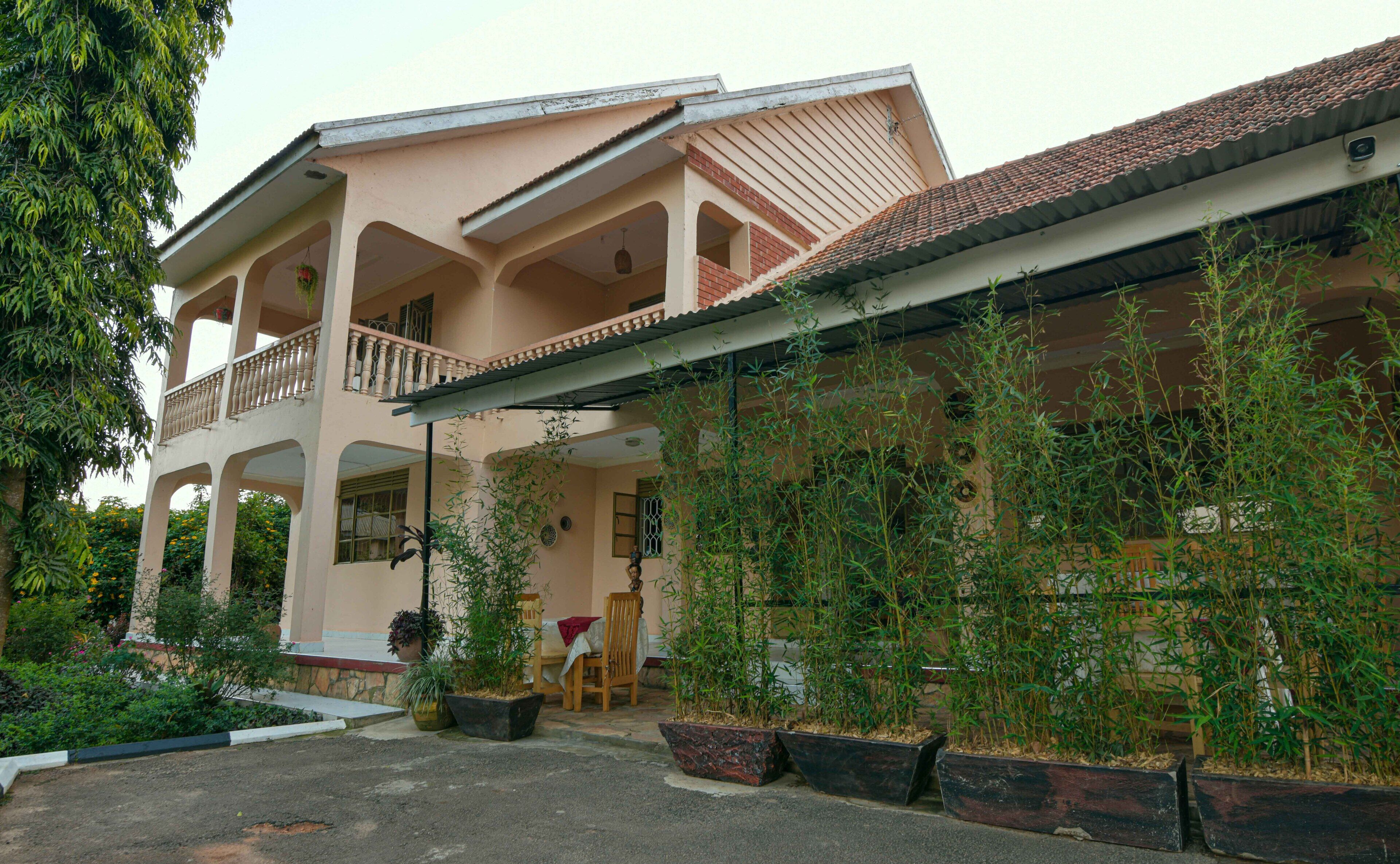 A two-story building with a balcony on the upper floor, surrounded by potted plants and a small seating area.