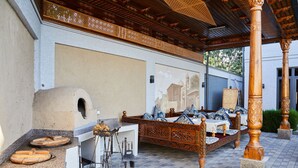 Un espace extérieur aménagé de manière traditionnelle, avec un four en pierre, des meubles en bois et un décor de plafond élaboré.