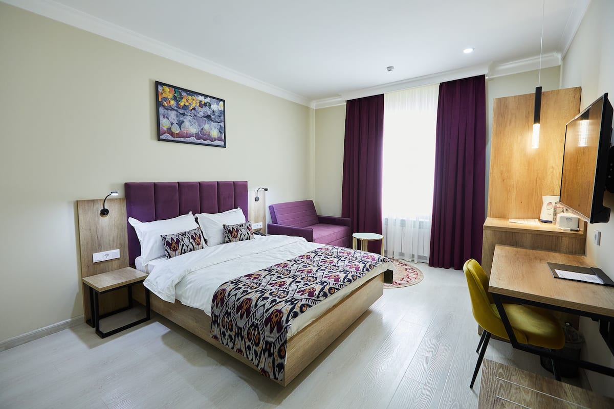 Una habitación de hotel moderna con una cama, un escritorio, una silla y una mesita.