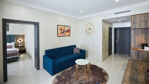 A modern living room with a blue sofa, a round coffee table, and a wall clock.