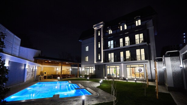 Un hôtel moderne doté d’une piscine, d’un patio couvert et d’une façade bien éclairée.