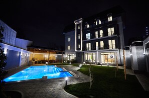 A modern hotel with a swimming pool, a covered patio, and a well-lit exterior. - OLD Tashkent Hotel&Spa (Tashkent)