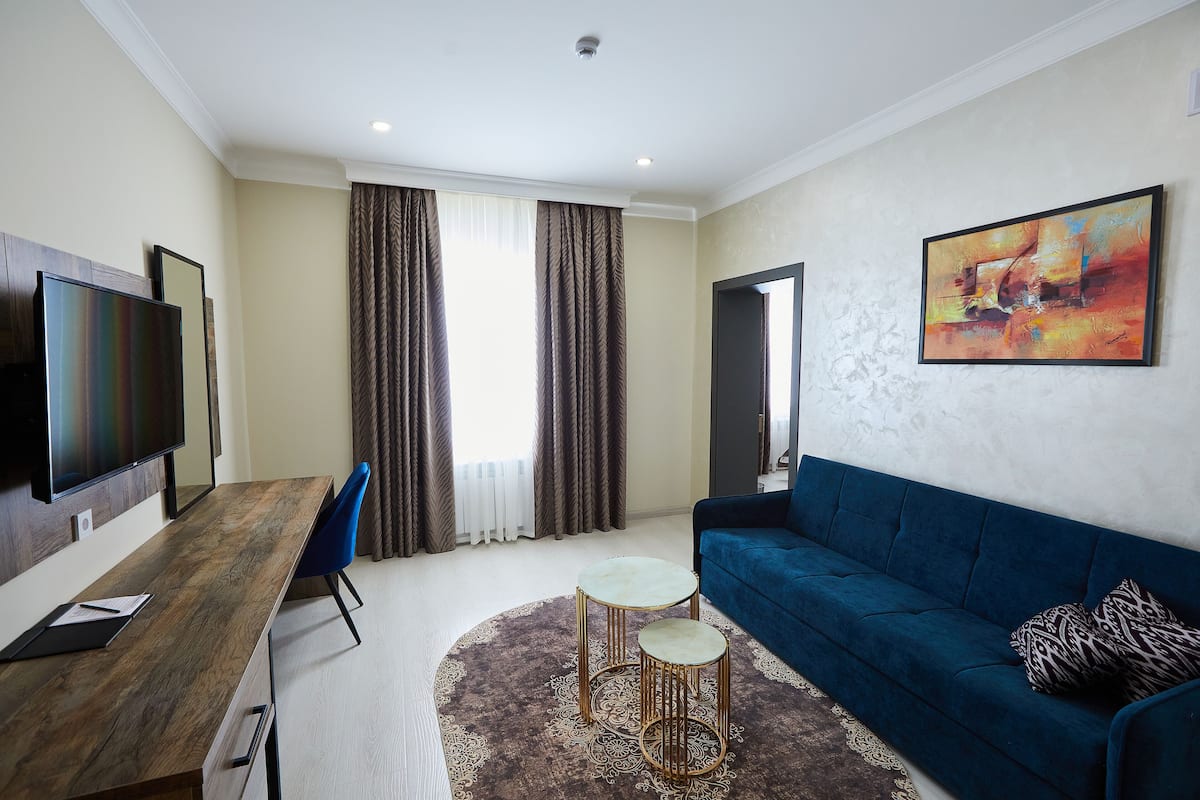 Una sala de estar moderna con un escritorio de madera, un sofá azul y un cuadro grande en la pared.