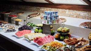 Un buffet proposant une variété de plats, notamment des fruits, des fromages et des pâtisseries.