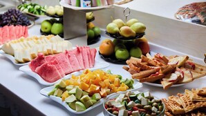 A buffet with various fruits, cheeses, and crackers.