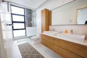 Een moderne badkamer met een grote spiegel, twee wastafels en een toilet.