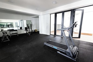 Een moderne sportschool met een loopband, gewichten en fitnessapparatuur.