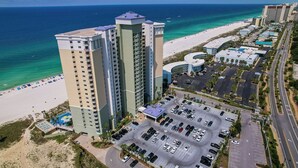 A high-rise hotel with a parking lot and beach view.
