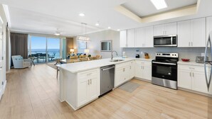 A modern kitchen with white cabinets, stainless steel appliances, and a large island.