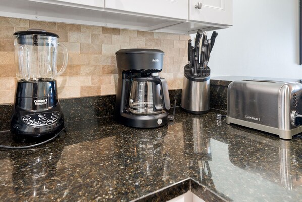 A kitchen counter with a Cuisinart SmartPower blender, a coffee maker, a knife block, and a toaster.