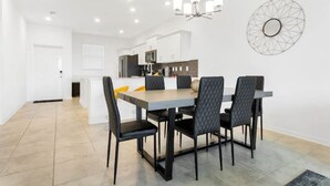 A modern dining area with a rectangular table, four black chairs, and a chandelier. - New Discount Disney Lazy River TikiBar Balcony (Kissimmee)