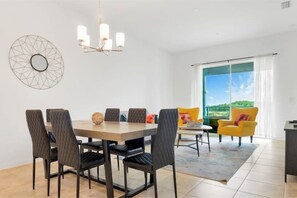 Un espace repas comprenant une table et des chaises, un lustre et une grande fenêtre donnant sur un beau paysage.