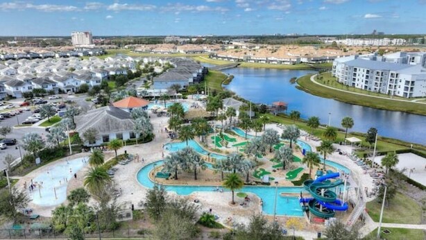 A resort with a large pool, water slides, and a lake. - New Discount Disney Lazy River TikiBar Balcony (Kissimmee)