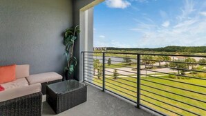 A balcony with a sofa, a coffee table, and a potted plant. - New Discount Disney Lazy River TikiBar Balcony (Kissimmee)