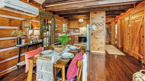 A wooden cabin interior with a dining area, kitchen, and a loft space. - Chic Boho Cabin in the Trees! (Ellijay)