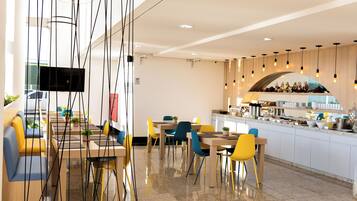A modern restaurant with a bar area, multiple seating options including booths and tables, and a visible kitchen counter.