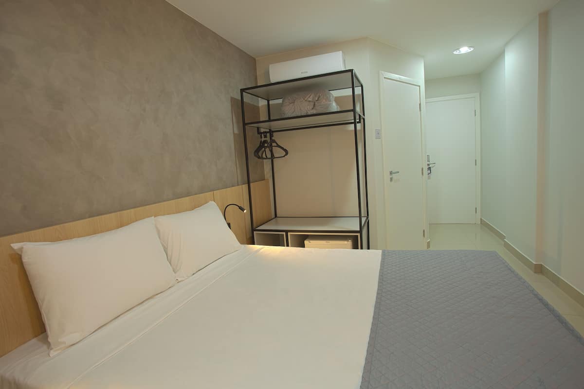 Habitació d'hotel amb un llit, una llitera, una taula de treball i un armari.