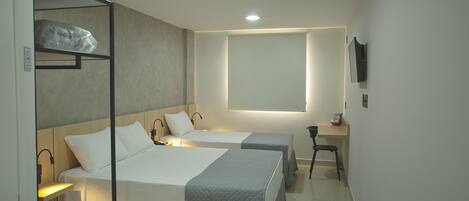 A hotel room with two beds, a desk, a chair, and a TV mounted on the wall.