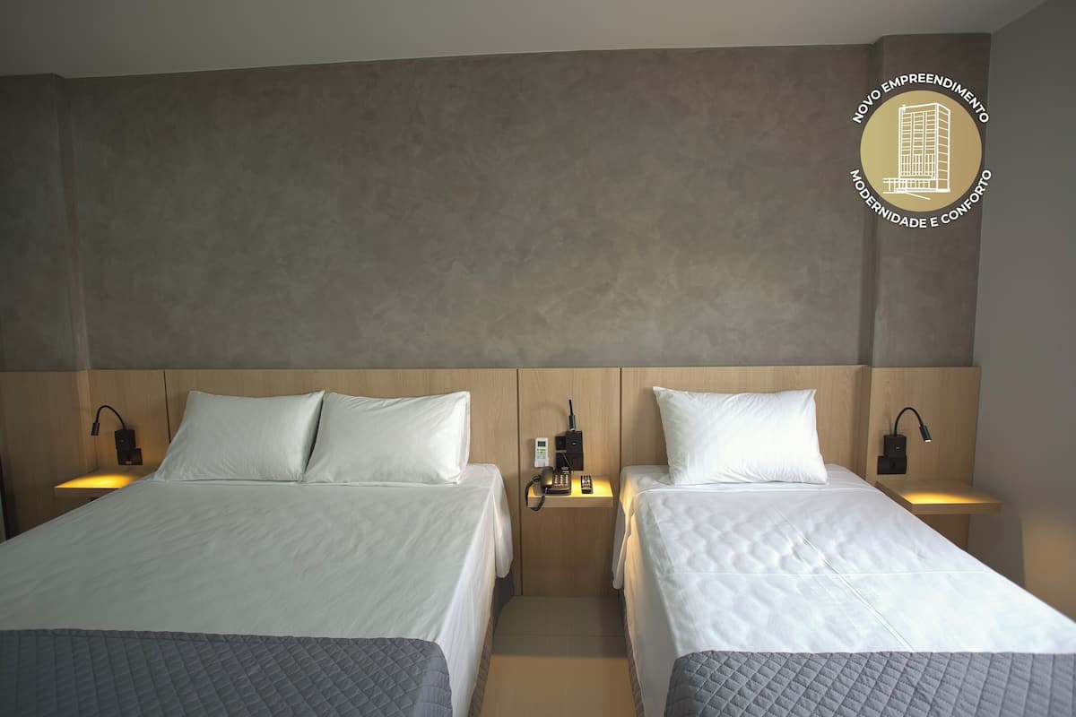 Una habitació d'hotel amb dos llits, cadascun amb un coixí i una taula de nit amb una làmpada.