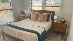 Un dormitorio con una cama de madera, dos mesitas de noche y una ventana con persianas.