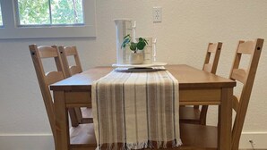 Una mesa de comedor con cuatro sillas de madera, un mantel a rayas y una planta en maceta sobre la mesa.