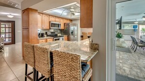 Eine moderne Küche mit Holzausstattung, einem Edelstahlkühlschrank und einer großen Kochinsel mit Barhocker.