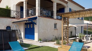 Ein zweistöckiges Gebäude mit überdachter Terrasse, Pool und Garten.