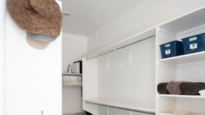 A walk-in closet with white shelving, a hanging rod, and storage boxes. - Home with Four Peaks  and  Mountain views just outside Tonto National Forest 
 (Rio Verde)