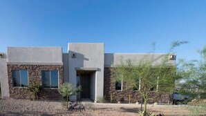 A modern two-story building with a stone facade and large windows. - Home with Four Peaks  and  Mountain views just outside Tonto National Forest 
 (Rio Verde)