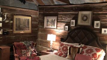 A rustic bedroom with a wooden headboard, a bed with patterned bedding, and a nightstand with a lamp.