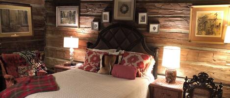 A rustic wooden room with a bed, two nightstands, and a chair.