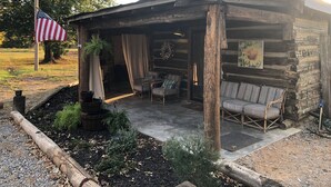 A rustic cabin with a porch, outdoor seating, and a flag. - Sunset Log Cabin (Clarksdale)