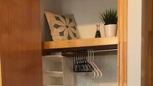 Een kast met houten frame, een ophangsysteem en een plank met decoratieve objecten.