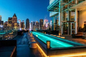 Ein Pool auf dem Dach mit Blick auf die Stadtlandschaft, moderne Architektur und Sitzgelegenheiten im Freien.