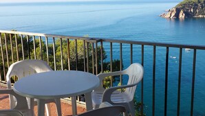 A balcony with a table and chairs overlooking a coastal view. - Comfortable apartments with swimming pool facing the sea. Ref. Cala Llevadó-46 (Tossa del mar)