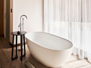 A modern bathroom with a freestanding bathtub, a small round table, and a faucet. - Letamo at Qwabi Private Game Reserve by Newmark (Thabazimbi)