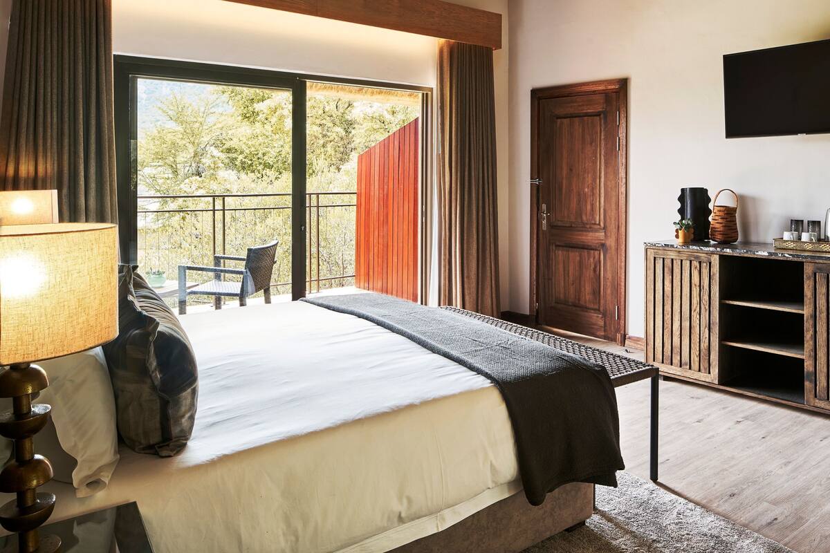 Une chambre à coucher comprenant un lit, un bureau, une chaise et un balcon avec des rideaux.