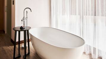A modern bathroom with a freestanding bathtub, a small round table, and a faucet.