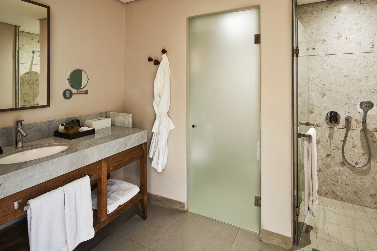 Une salle de bain équipée d’un meuble-lavabo, d’un miroir, d’un porte-serviettes et d’un espace douche.