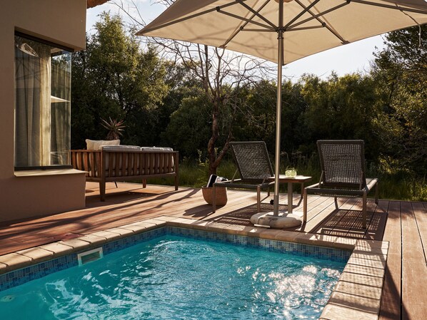 A poolside area with a wooden deck, a lounge chair, a table, and an umbrella. - Letamo at Qwabi Private Game Reserve by Newmark (Thabazimbi)