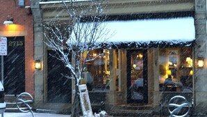 A building with a snow-covered entrance and a visible sign indicating a loading zone.