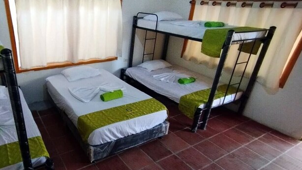 Un dormitorio con literas, una ventana con cortinas y suelo de baldosas.