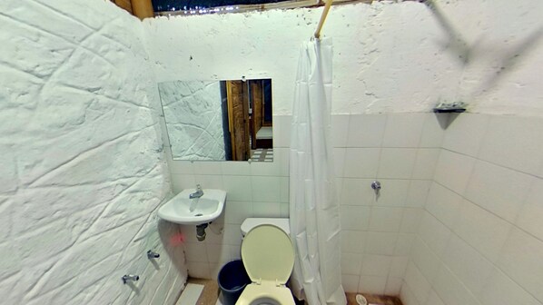 A small, compact bathroom with white walls, a sink, a toilet, and a shower curtain. - Eco Hotel Guarumal (Carmen de Apicala)