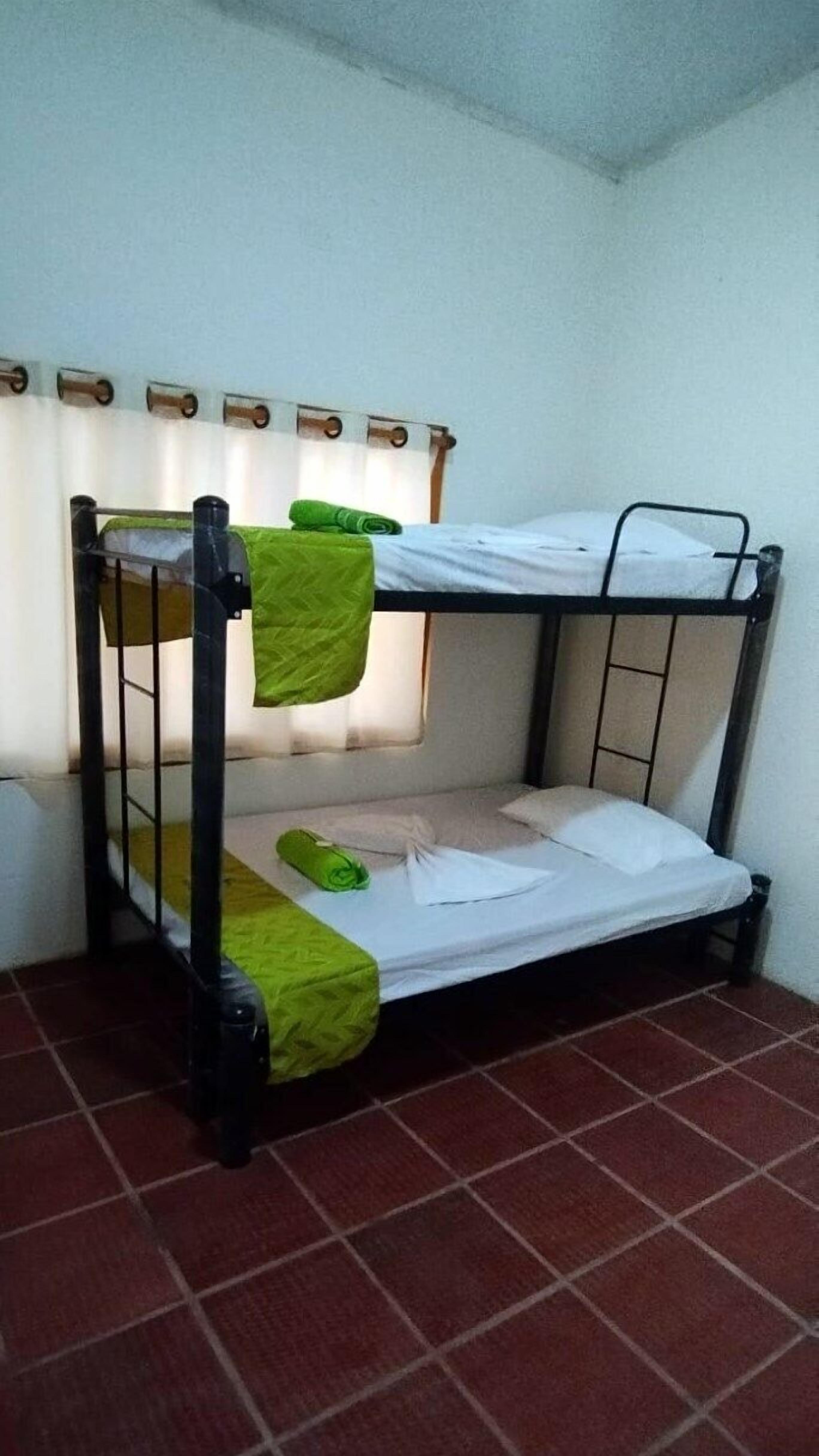 A bunk bed with green bedding and a curtain.