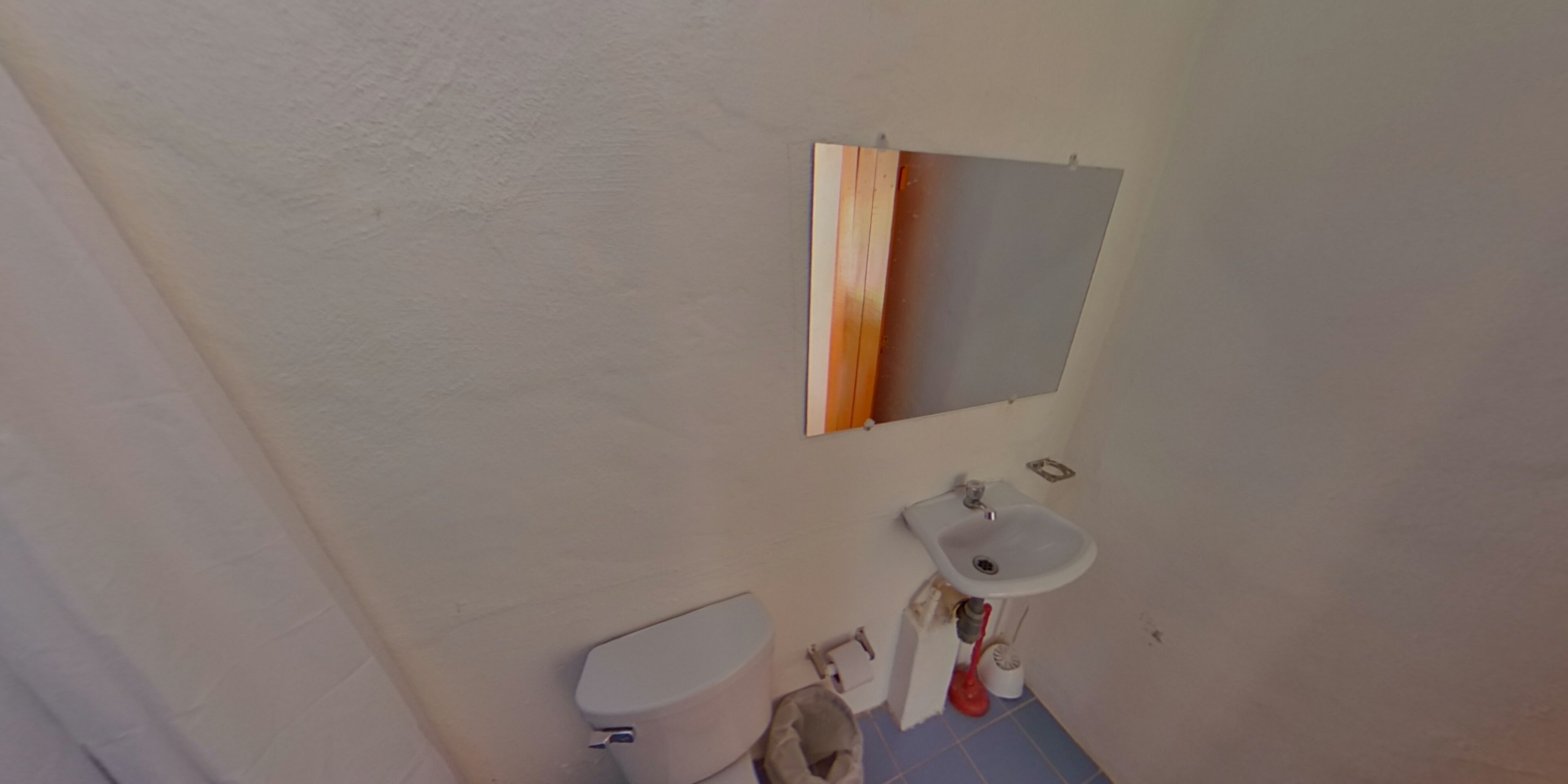 Un baño con inodoro, lavabo y espejo.