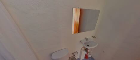 Un baño con inodoro, lavabo y espejo.